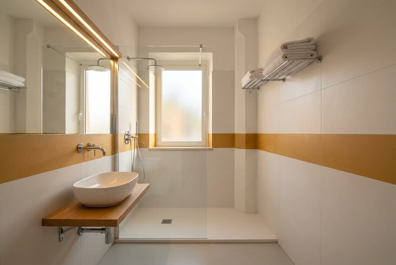Visualizzazione di progetto: bagno con doccia, lavabo e rivestimenti chiari